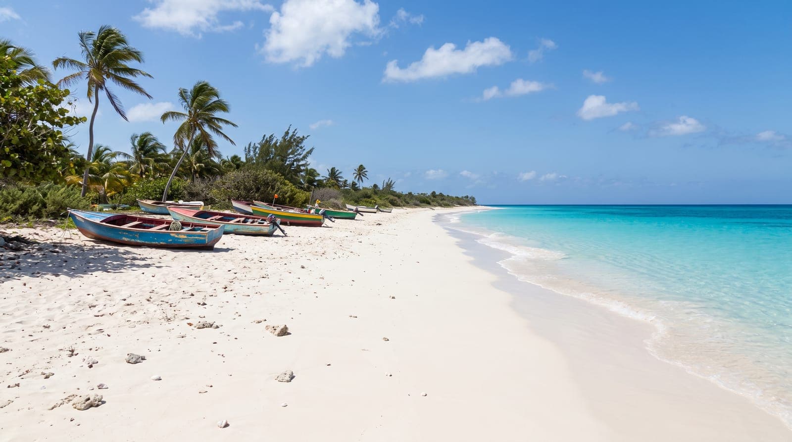 Weißer Sandstrand auf Anguilla, türkisfarbenes Meer, Kokospalmen und bunte Fischerboote