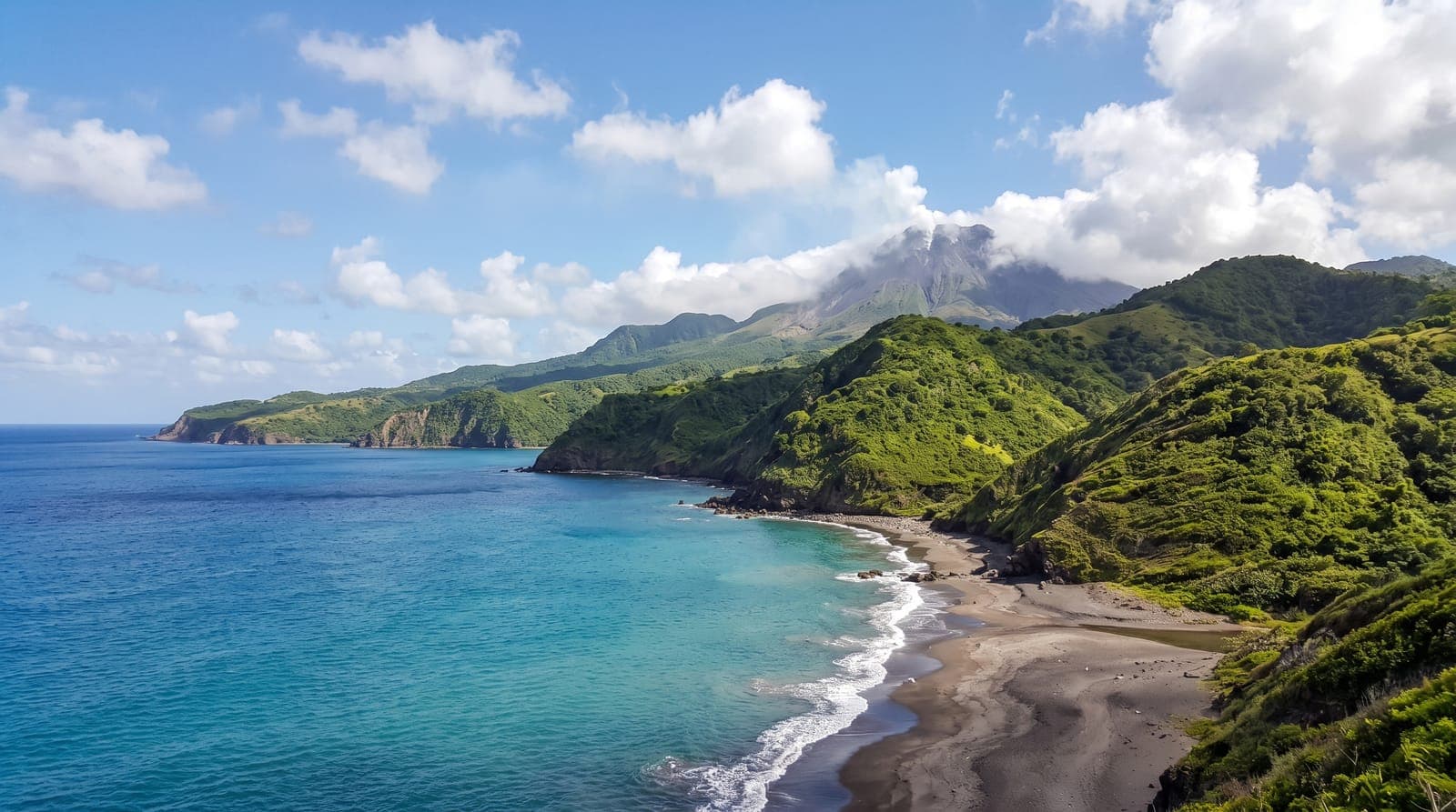 Grüne Küste von Montserrat, dunkler Vulkansandstrand, türkisfarbenes Meer und ein Vulkan im Hintergrund