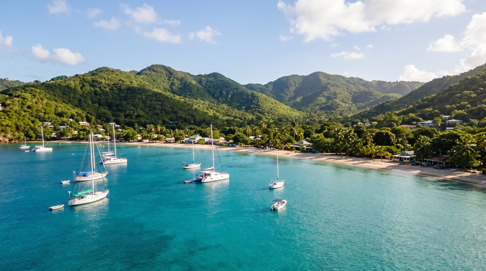 Ruhige Bucht von Bequia in den Grenadinen, Segelboote vor Anker auf türkisfarbenem Wasser vor Hügeln mit tropischer Vegetation